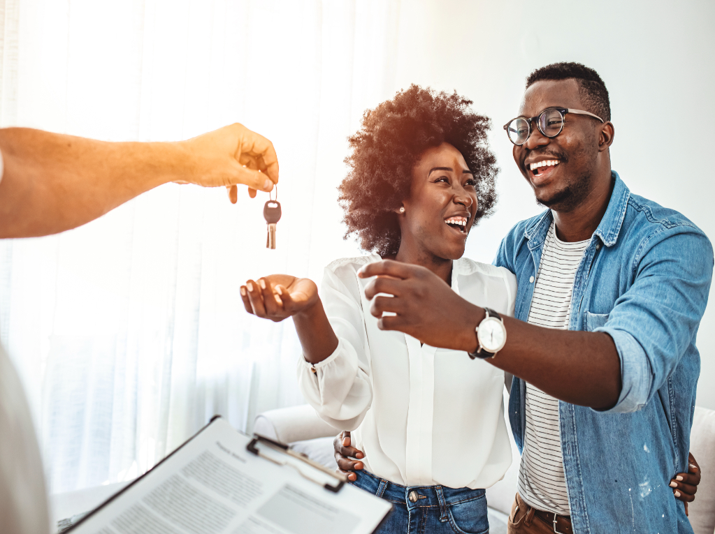 Happy couple is taking keys from their new house from broker and smiling